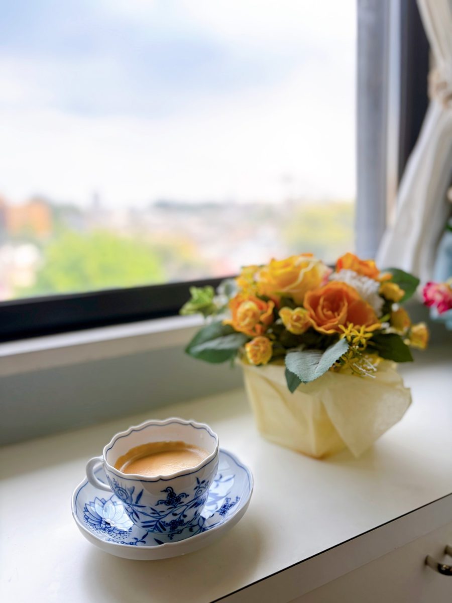 窓辺に置いたコーヒーカップと、オレンジと黄色の花